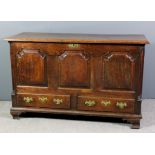 A mid 18th Century panelled oak mule chest, the plain lid with moulded edge, the front with three