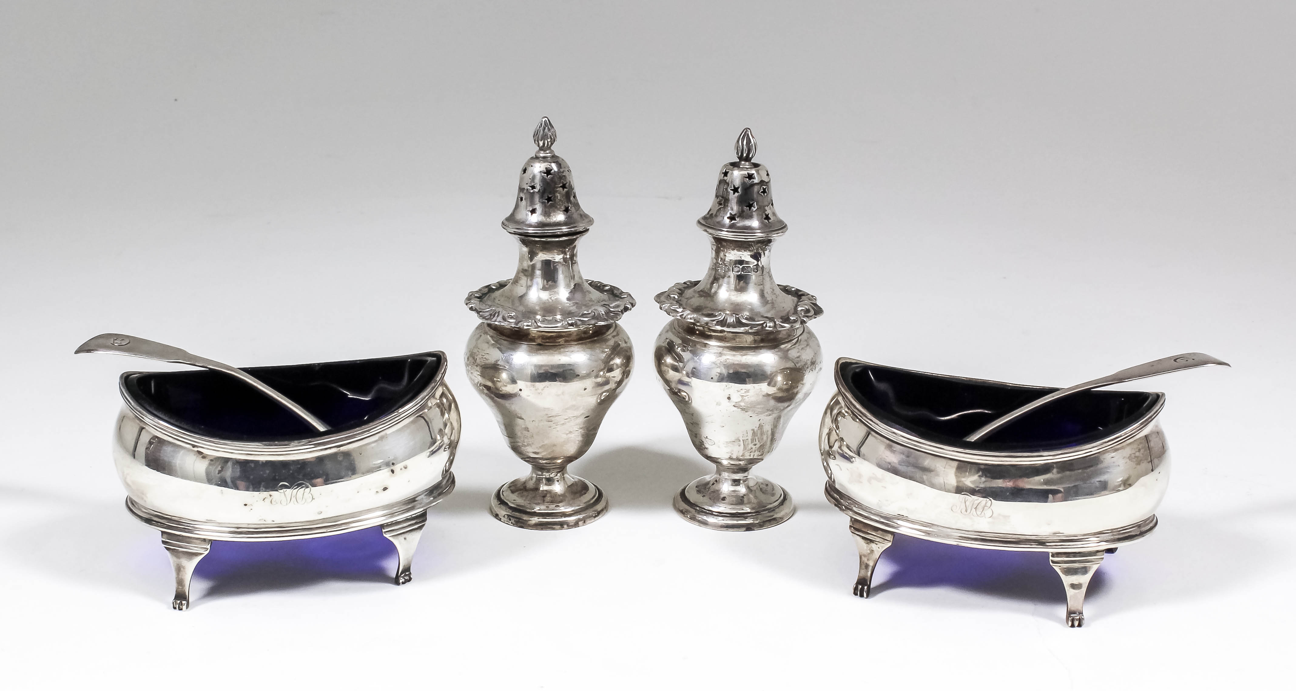 A pair of George III oval salts with slightly bulbous sides and reeded mounts, each on four scroll