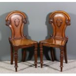 A pair of Victorian mahogany hall chairs, the shaped and moulded backs with applied shield shaped