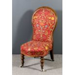 A late Victorian walnut framed spoon back nursing chair upholstered in red floral cloth, on turned