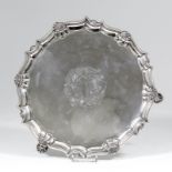 A George II silver circular salver, the moulded piecrust rim with cast shell ornament, on three