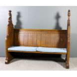 A Victorian oak church pew with moulded crest rail and panelled back, on shaped end supports, the