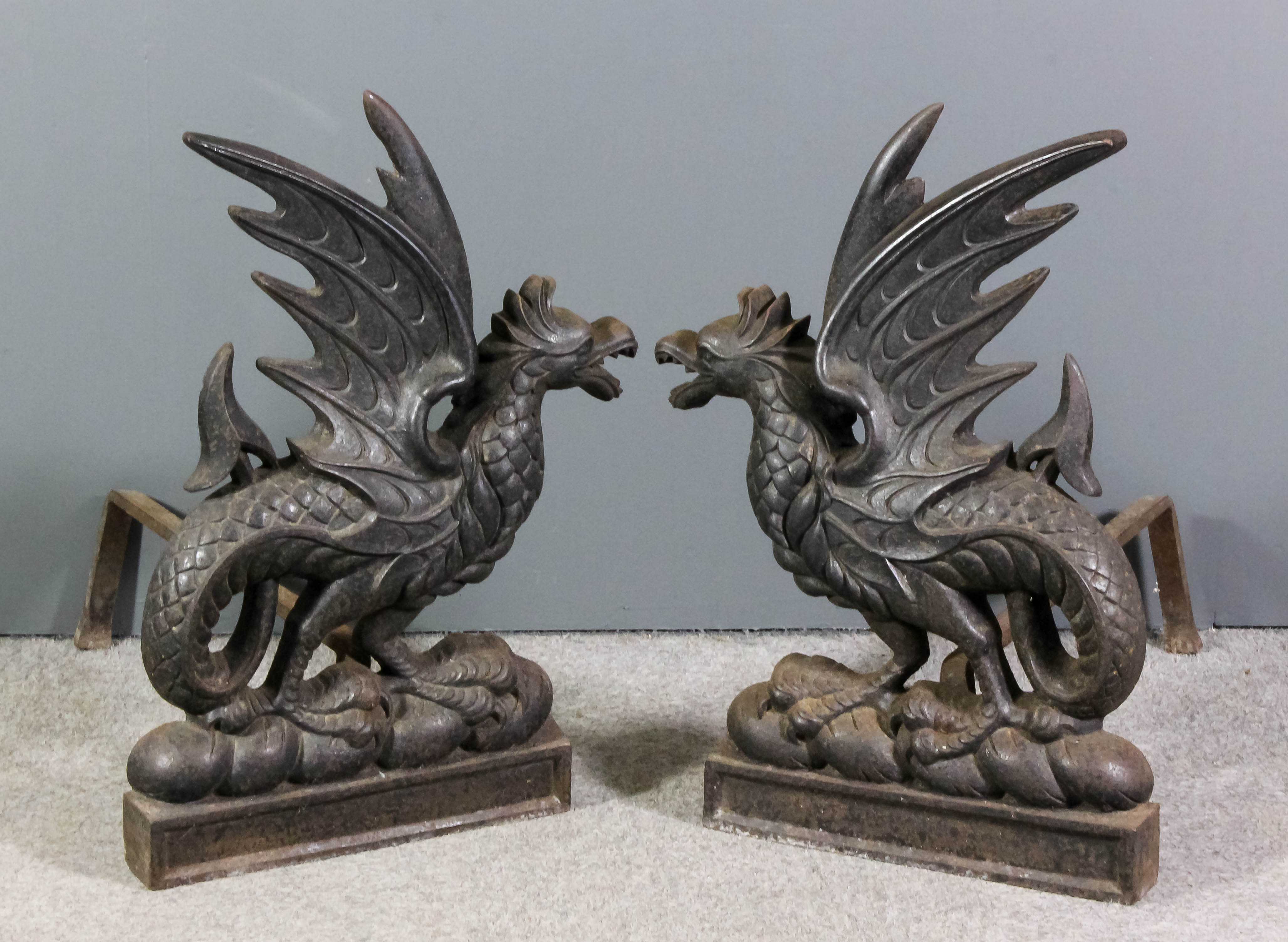A pair of Victorian cast iron andirons cast in the form of seated griffins on plinth bases, 30ins