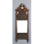 A near Eastern hardwood rectangular mirror with shaped top, profusely carved, pierced and turned