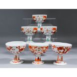 Three Chinese red and white porcelain circular stem cups each decorated with dragons chasing the