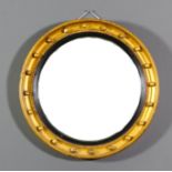 A gilt framed circular convex wall mirror, the deep moulded frame with ball ornament and ebonised