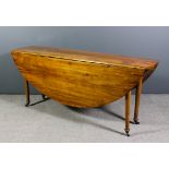 A 19th Century French fruitwood oval drop-leaf dining table on turned supports and castors, 72ins