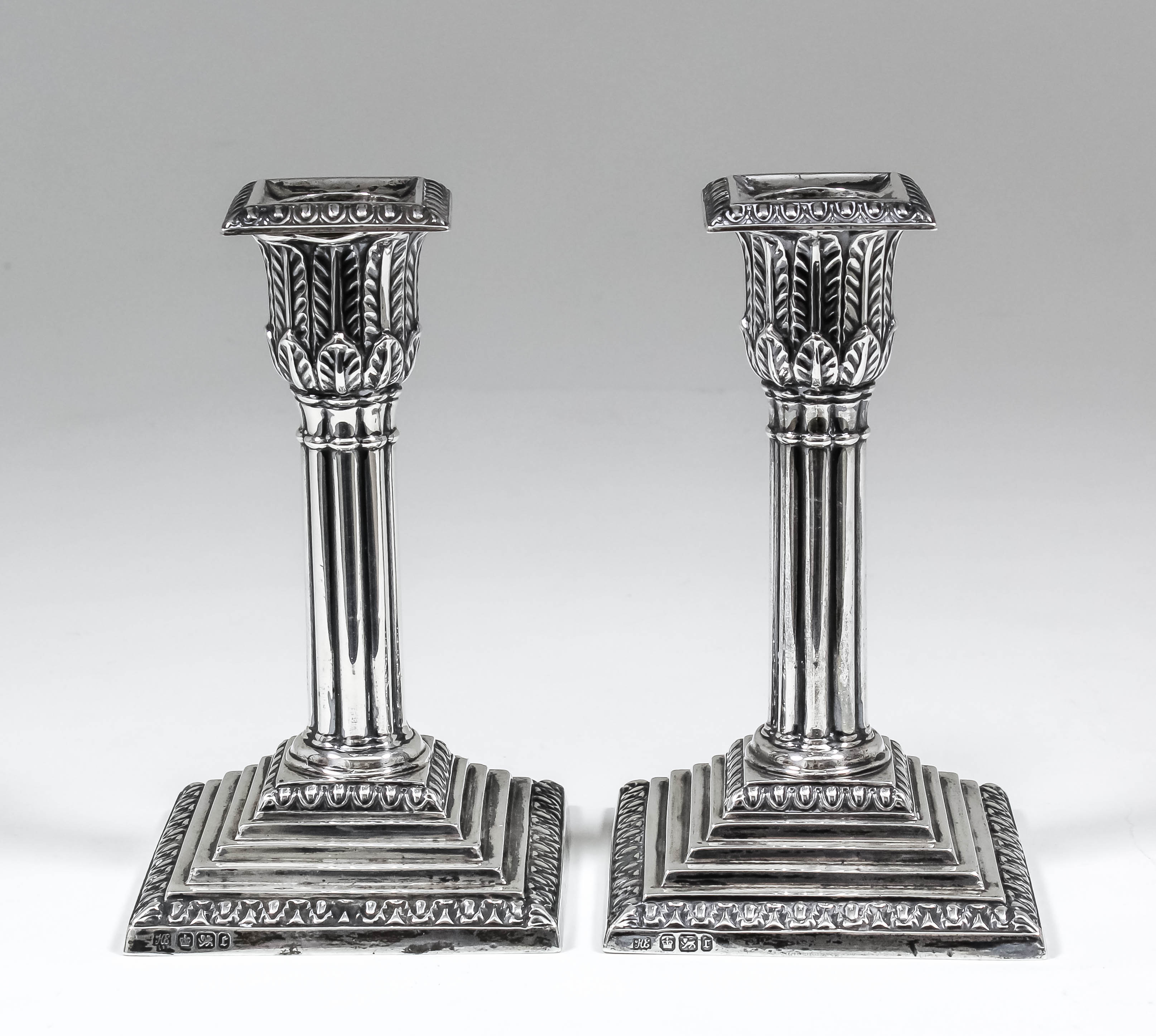 A pair of Edward VII silver pillar candlesticks with oval bead mounts, leaf cast capitols and reeded