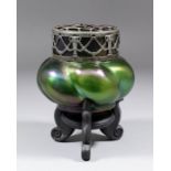 An Art Nouveau six lobed glass pourri vase and silvered metal pierced cover of dark green iridescent