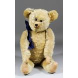 An early 20th Century American blond mohair teddy bear with black button eyes and hump, 21.25ins