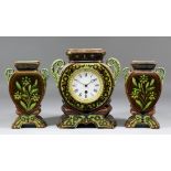 A Continental brown and green glazed pottery clock garniture, the timepiece with 3.5ins diameter