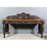 A late Victorian oak sideboard/hall table, the shaped back fretted and carved with flowerhead and