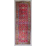 A Malayer runner woven in colours with five hooked lozenge shaped medallions and stylised leaf