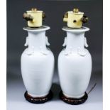 A pair of Chinese Blanc de Chine porcelain baluster shaped vases moulded with dragons to the