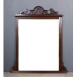 A late Victorian walnut framed overmantel mirror, the arched and shaped cresting carved with leaf