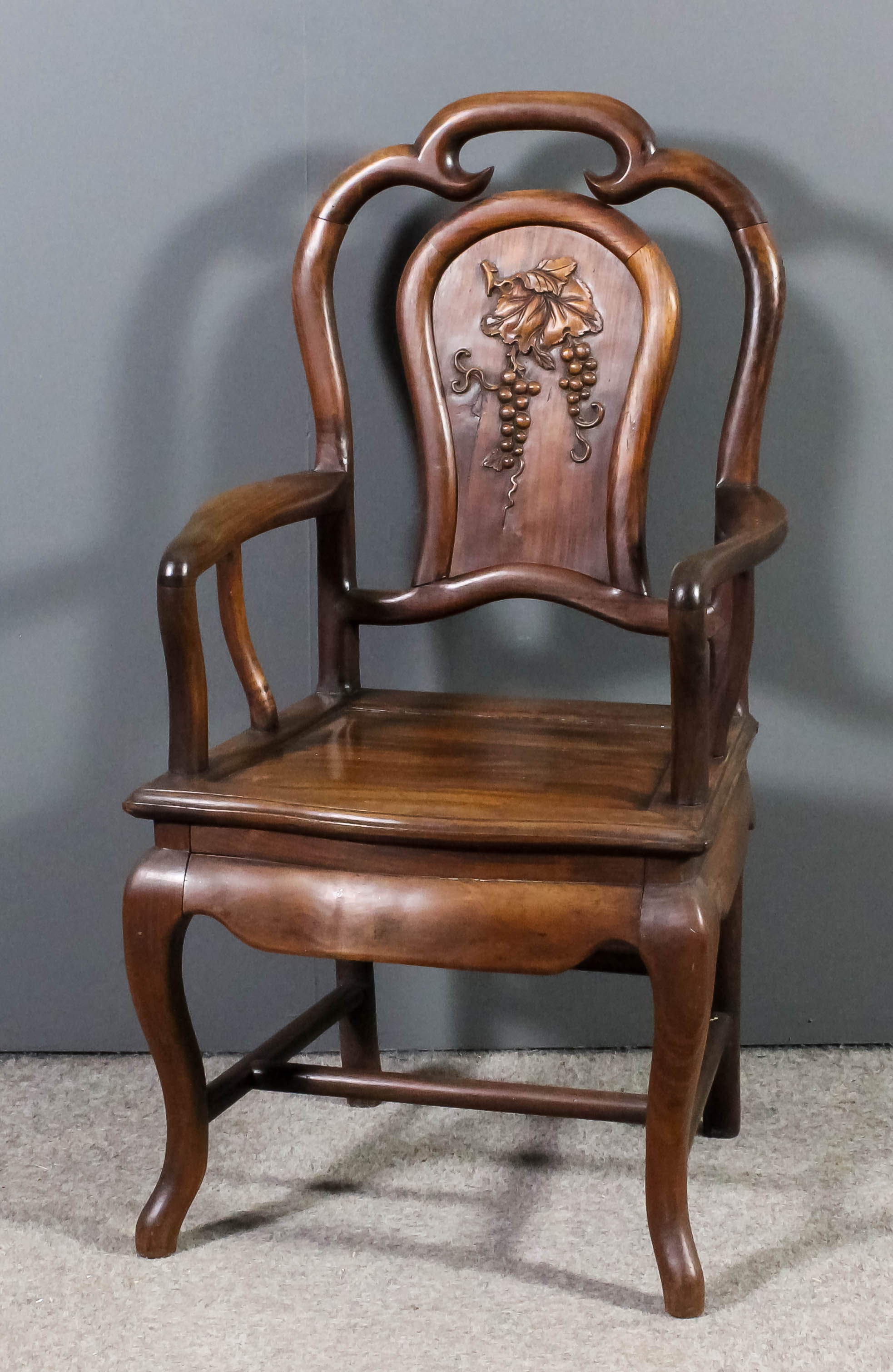 A late 19th/early 20th Century Chinese rosewood open armchair, the shaped back inset with panel
