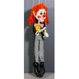 A large Pelham puppet painted as a composition and wood clown, wearing orange wig and yellow