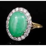 A modern 18ct gold and platinum mounted jade and diamond ring, the central oval cut cabochon stone