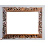 A late Victorian oak framed rectangular wall mirror, the frame boldly fretted and carved with floral