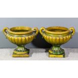 A pair of green glazed pottery two garden urns with leaf scroll handles and partly reeded bodies, on