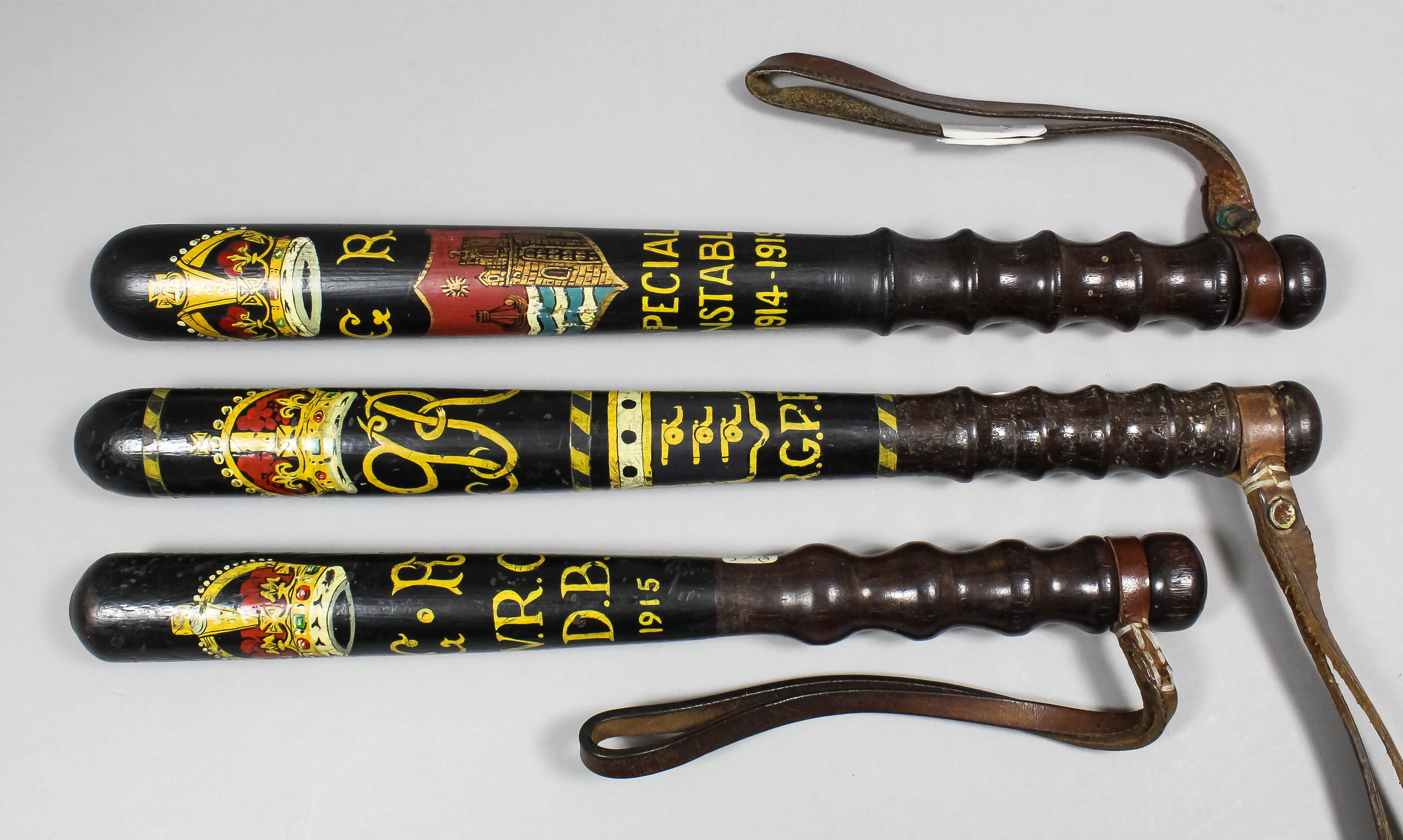 A George V turned wood truncheon painted with a crown over the royal cipher above arms bearing three