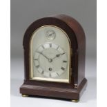 A 1920s mahogany cased timepiece with arched silvered dial with Roman numerals to the eight day
