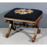 A Victorian walnut framed rectangular stool, the seat upholstered in floral needlework, on moulded