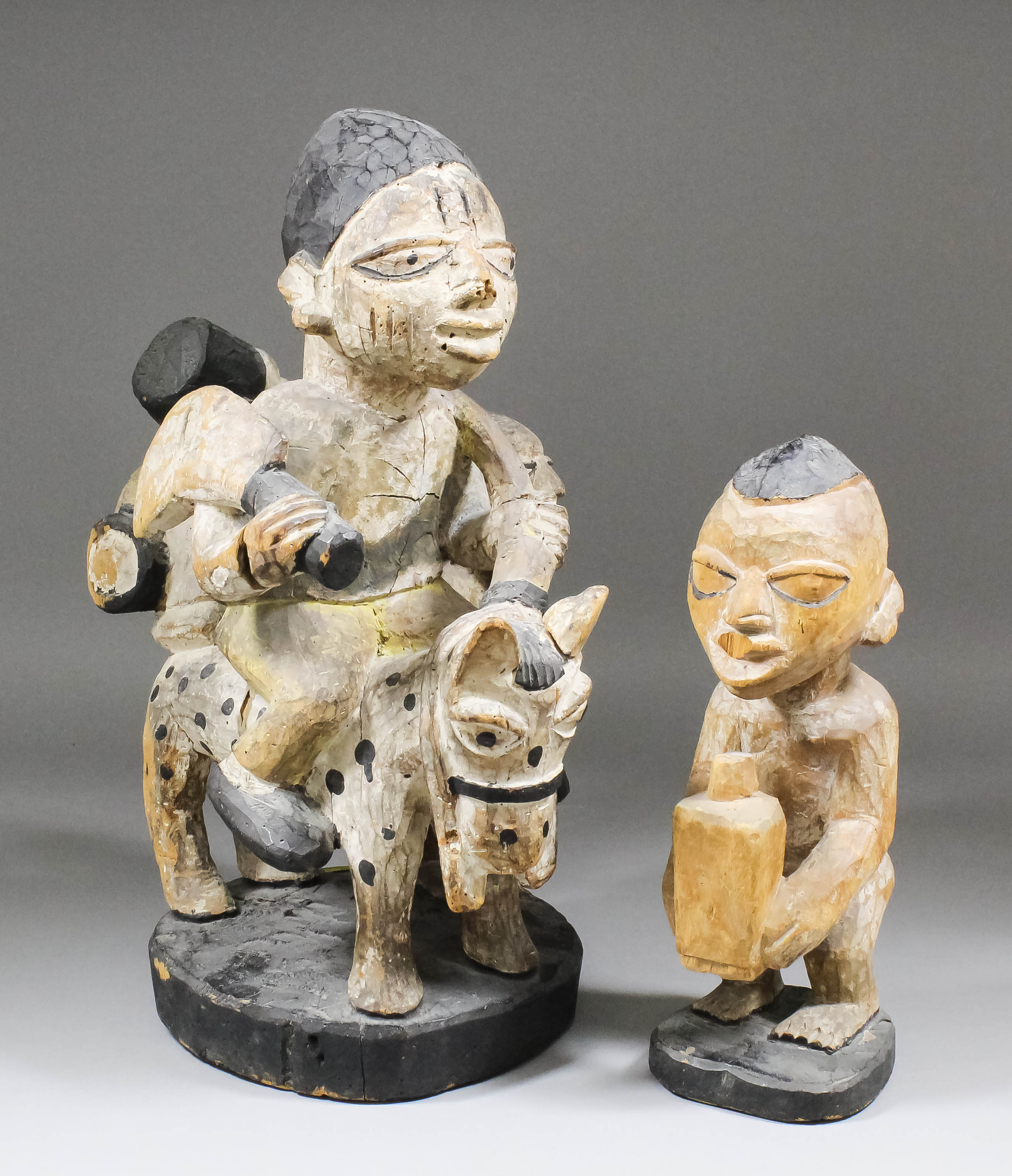 A Yoruba carved and painted wood group - Male figure on horseback with two attendants, 19ins high,