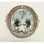 PALE AQUAMARINE AND DIAMOND SET 14CT WHITE GOLD RING, the four claw set oval mixed cut aquamarine