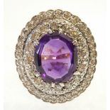 AMETHYST AND DIAMOND CLUSTER RING, the oval mix cut amethyst with a two tier illusion set surround