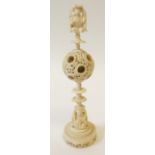 EARLY TWENTIETH CENTURY CHINESE CARVED IVORY PUZZLE BALL, to the centre of a turned stem, surmounted