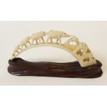 CARVED BOAR TUSK, FASHIONED AS A BRIDGE OF ELEPHANTS, 6 ž" (17.2cm) long, on stand