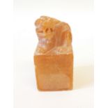 *CHINESE AMBER STAINED ALABASTER SEAL, the tall block base surmounted by a carved lion dog, 3" high,