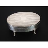 ENGINE TURNED SILVER OVAL TRINKET BOX, hinged lid, plush lined interior and raised on four scroll