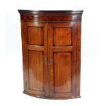GEORGE III LATE 18TH CENTURY OAK AND MAHOGANY CROSSBANDED BOW FRONT HANGING CORNER CUPBOARD, with