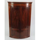 EARLY 19TH CENTURY LINE INLAID FIGURED MAHOGANY BOW FRONTED CORNER CUPBOARD the dentil moulded