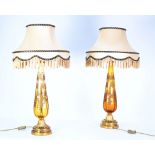 PAIR OF TALL GILT METAL AND AMBER GLASS TABLE LAMPS gilt floral decorated and the fringed silk