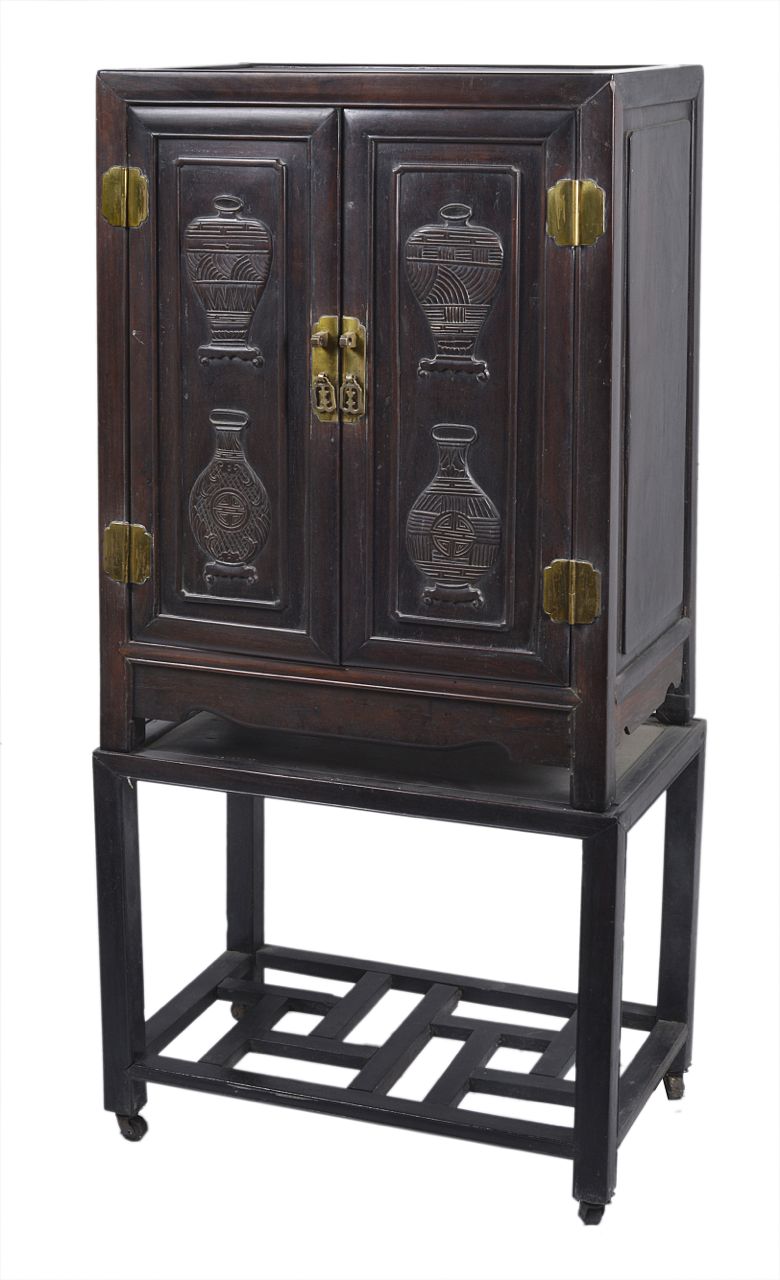 A late 19th century Chinese hardwood cabinet, the front with carved panels to the doors depicting
