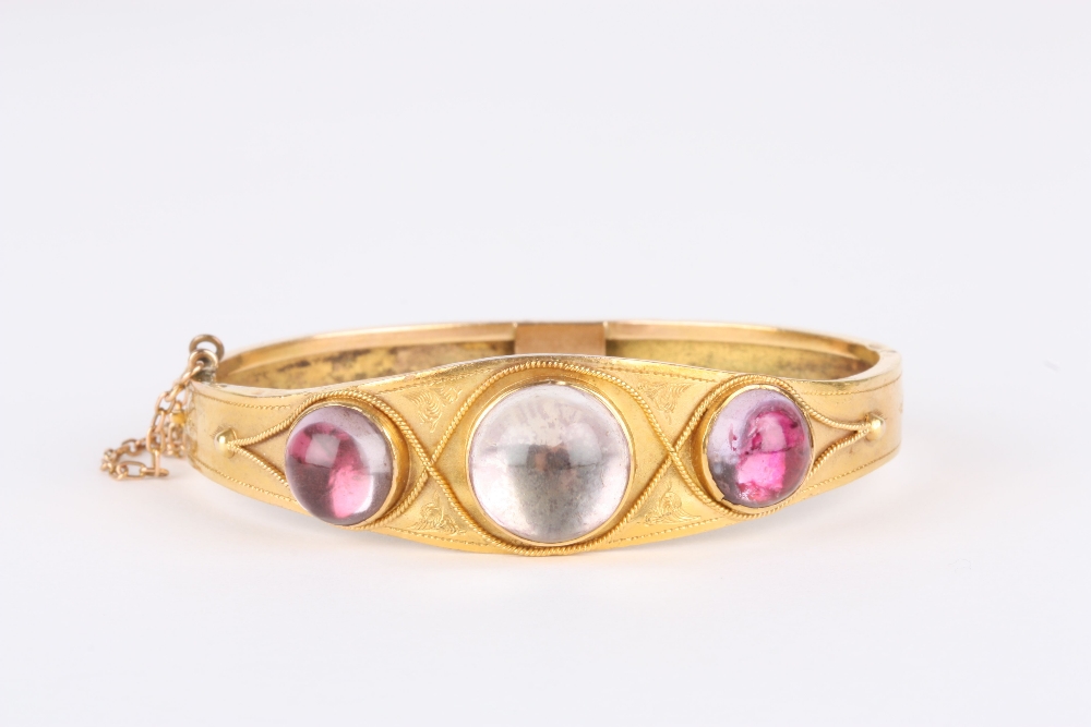 A Victorian yellow metal stiff bangle, set with three cabochon foil backed stones, the metal