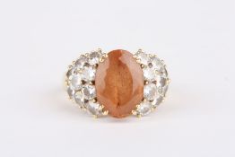 An 18ct gold and diamond cluster ring, set with central oval coloured quartz stone, flanked either