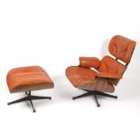A Charles and Ray Eames rosewood and orange leather lounge chair and ottoman, models 670 and 671
