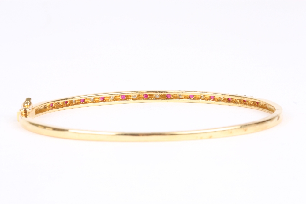 An 18ct gold, diamond and ruby stuff bangle, set with eleven diamonds interspersed by twelve - Image 2 of 2