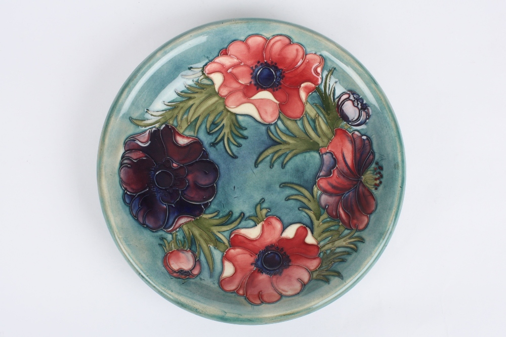 A Moorcroft anemone pattern plate, the purple and pink painted flowers on a turquoise ground, with
