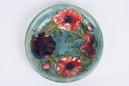 A Moorcroft anemone pattern plate, the purple and pink painted flowers on a turquoise ground, with