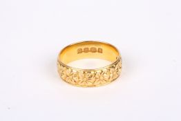 An 18ct gold wedding band, decorated all round with flower heads. 5.9 grams. Size O ½ . Good
