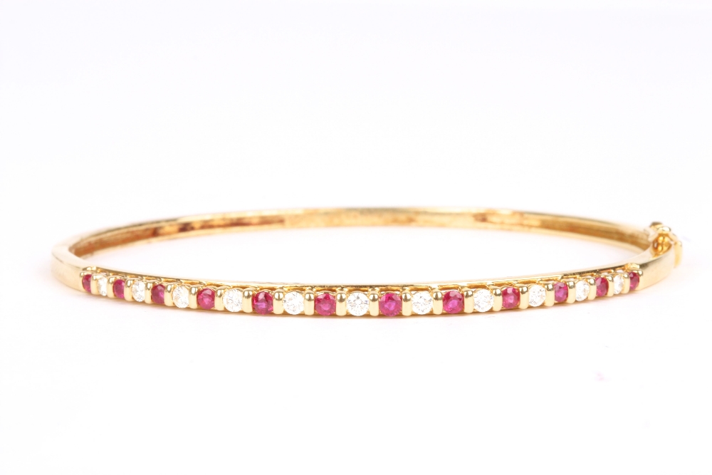 An 18ct gold, diamond and ruby stuff bangle, set with eleven diamonds interspersed by twelve