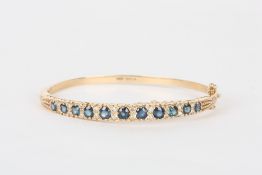 A 9ct gold Victorian style sapphire and diamond stiff bangle, set with eleven graduated sapphires