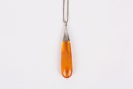 An amber drop pendant, of elongated form, with white metal mount and chain, length 7cm . in good