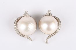 A large pair of pearl and diamond earrings, each set with a large central pearl and crested with a