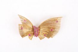 An 18ct gold and ruby brooch in the form of a bow, with central knot set with two rows of rubies,